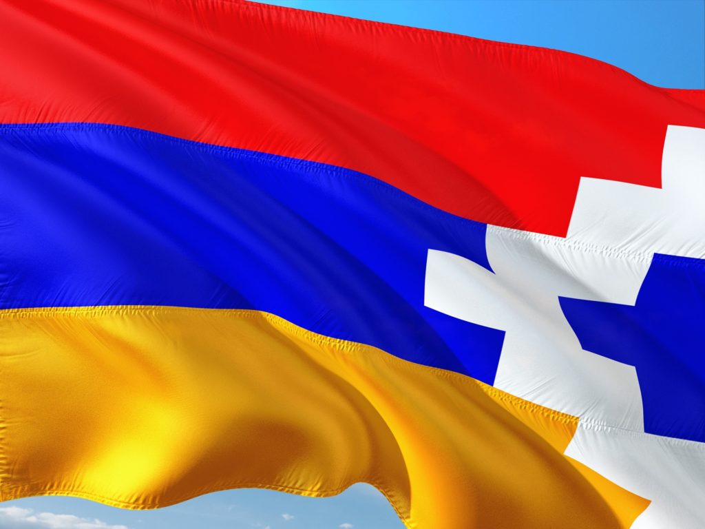 Vlajka Arcachu je stejně jako arménská vlajka tvořena třemi horizontálními pruhy – červeným, modrým a žlutým. Zobrazuje však navíc bílé obdélníky uspořádané do tvaru trojúhelníku.